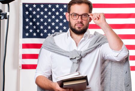 Smiling young man on United States flag background. Student is learning English as a foreign language. American flag.の写真素材