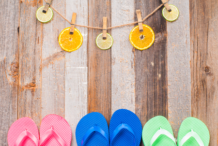 Pink, blue and green flip flop sandals on wood background. Citrus fruits.の写真素材