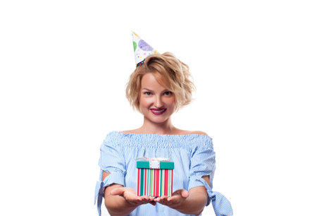 Beautiful happy woman in a celebratory cap with gift box at celebration party. Birthday celebrating...