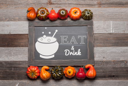Pumpkins and fallen leaves on wooden background. Chalkboard. Halloween, Thanksgiving day or seasonal autumnal.の写真素材