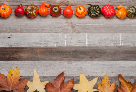 Pumpkins and fallen leaves on wooden background. Copy space for text. Halloween, Thanksgiving day or seasonal autumnal.の写真素材