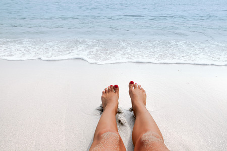 Female feet on sandy ocean beach. Vacation on the beach, legs on seashoreの写真素材