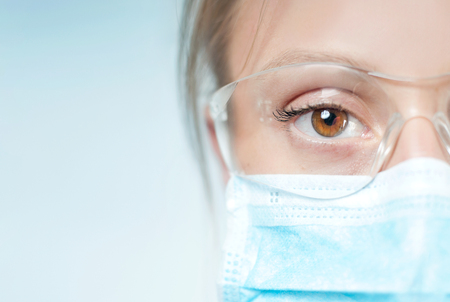 Portrait of young specialist with protective glasses and mask. Half face and eyeの写真素材