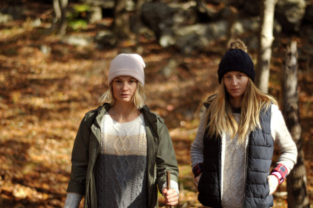 Hiking, camp, adventure, traveling and friendship concept. Girls walking in autumn forest in the mountains.の写真素材