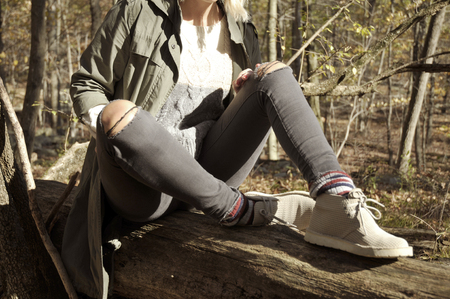 Girl is sitting in autumn forest in the mountains. Hiking, camp, adventure, traveling and friendship concept.の写真素材