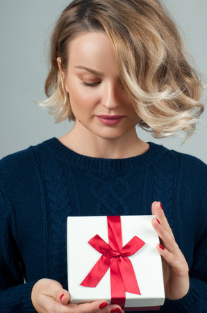 Christmas and New Year.  Woman in warm sweater and hat is holding christmas giftの写真素材