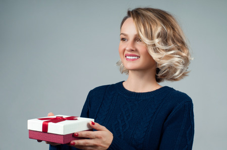 Christmas and New Year.  Woman in warm sweater and hat is holding christmas giftの写真素材