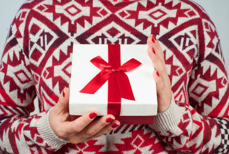 Christmas and New Year.  Woman in warm sweater is holding christmas gift