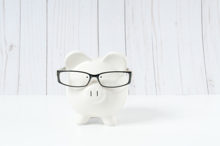 Front view. White piggy bank in glasses isolated on whiteの写真素材