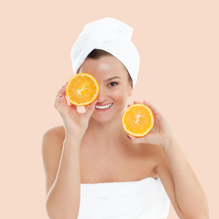 Beauty and spa. Beautiful woman with clean fresh skin is holding orange on pastel backgroundの写真素材