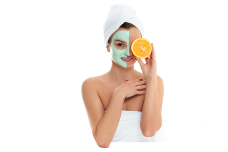 Beautiful woman is getting facial clay mask on white background. Beauty, body care and spa conceptの写真素材