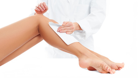 Beauty Spa. Hair removal cosmetology procedure. Beautician waxing a female leg applying a strip of material over the hot wax の写真素材