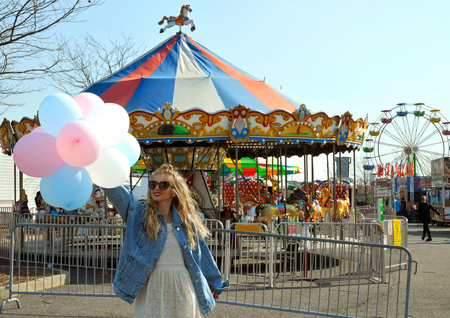 Beautiful young woman with colorful balloons in the amusement park の写真素材