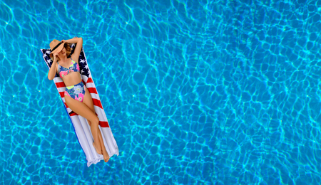 Summer Vacation. Enjoying suntan Woman in bikini on the inflatable mattress in the swimming pool. の写真素材