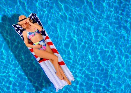 Summer Vacation. Enjoying suntan Woman in bikini on the inflatable mattress in the swimming pool. の写真素材
