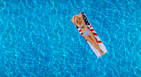 Summer Vacation. Enjoying suntan Woman in bikini on the inflatable mattress in the swimming pool. の写真素材