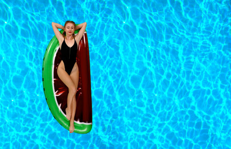 Summer Vacation. Enjoying suntan Woman in bikini on the inflatable mattress in the swimming pool.