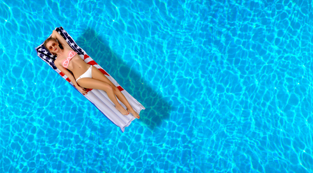 Summer Vacation. Enjoying suntan Woman in bikini on the inflatable mattress in the swimming pool.の写真素材