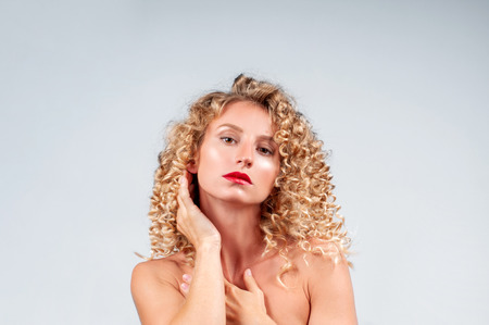 Happy girl with healthy curly hair. Beautiful woman with wavy blonde hair.の写真素材
