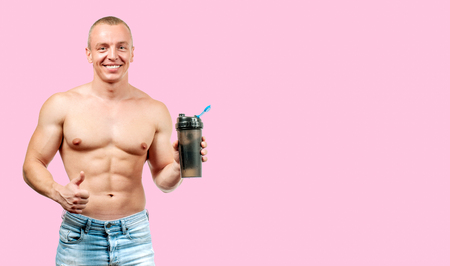 Handsome muscular man taking protein sports nutrition on pink backgroundの写真素材