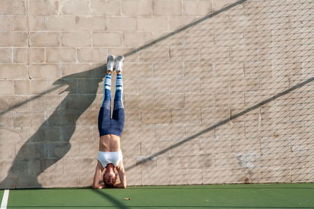 Healthy lifestyle and yoga concepts. Fitness woman in sportswear is doing exercise, stretches on the wallの写真素材