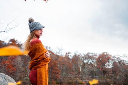 Woman traveler in warm hat and autumn clothes looking at amazing lake and forest, wanderlust travel conceptの写真素材