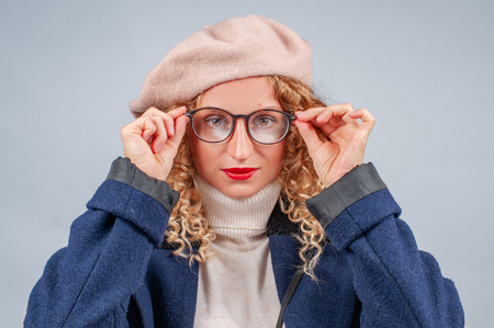 Happy student woman in eyeglasses and beret is smiling and looking at cameraの写真素材