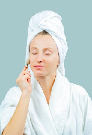 Face massage. Facial beauty treatment. Beautiful woman getting massage face using roller massagerの写真素材