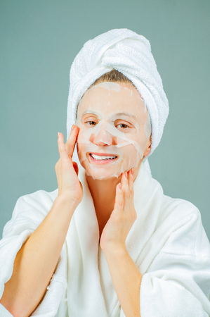 Facial care and beauty treatments. Beautiful woman with a sheet moisturizing mask on her face. Cosmetic procedure.の写真素材