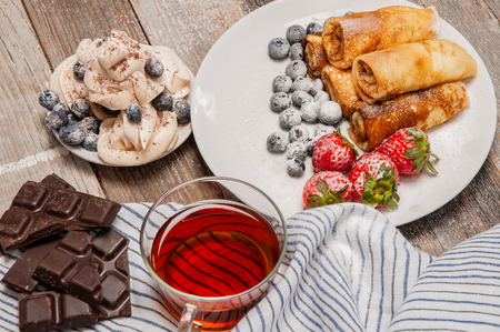 Healthy breakfast, black tea and delicious homemade pancakes with fresh berries on wooden tableの写真素材