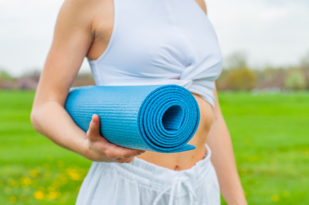 Beautiful woman is holding a yoga mat outdoors. Yoga and fitness conceptの写真素材
