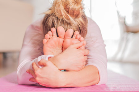Young woman practicing yoga, seated forward bend pose, doing paschimottanasana exercise