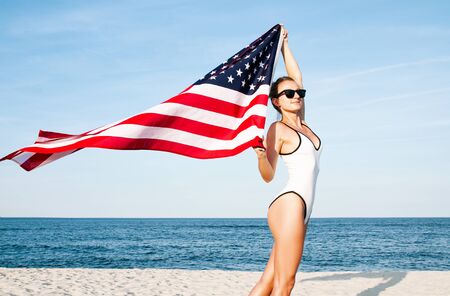 Beautiful patriotic woman holding an American flag on the beach.  USA Independence day, 4th July. Freedom conceptの写真素材