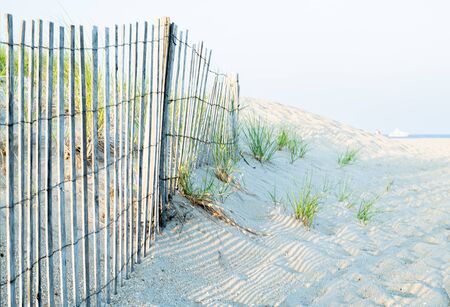 Wooden fence along the dune line on the beach in summer day. Travel and vacation.の写真素材