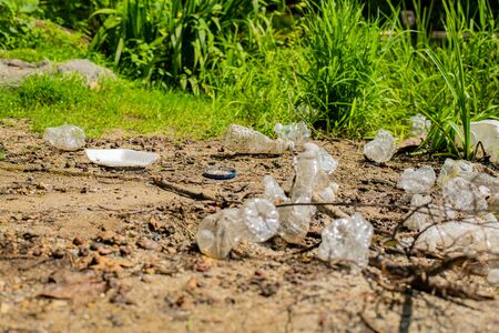 Trash and used plastic bottles in the river. Garbage near lake. Environmental pollution. Ecological problemの写真素材
