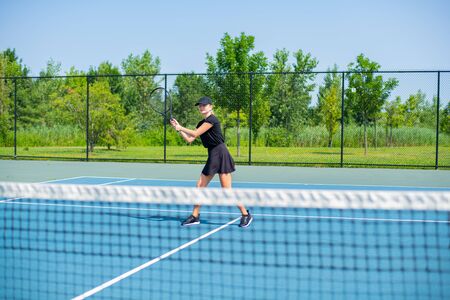 Beautiful sports woman playing tennis on the blue tennis courtの写真素材