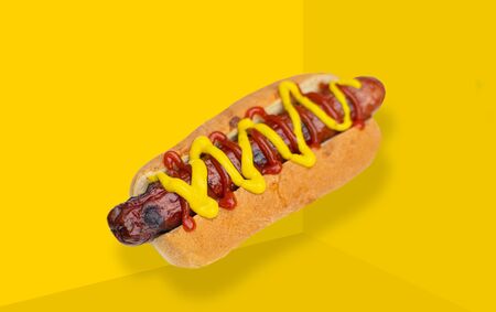 Hot dog with mustard on yellow background. Fried sausage in bread.の写真素材
