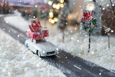 Miniature classic car carrying a christmas gifts on snowy winter magic landscapeの写真素材