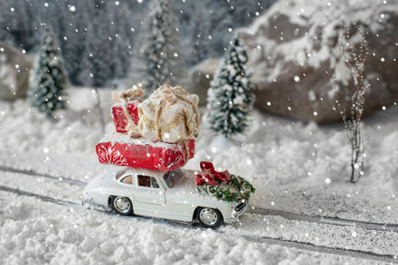 Miniature classic car carrying a christmas gifts on snowy road on magic winter landscapeの写真素材