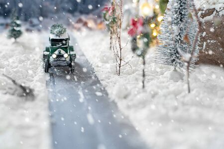 Miniature classic car carrying a christmas tree on snowy road on winter backgroundの写真素材