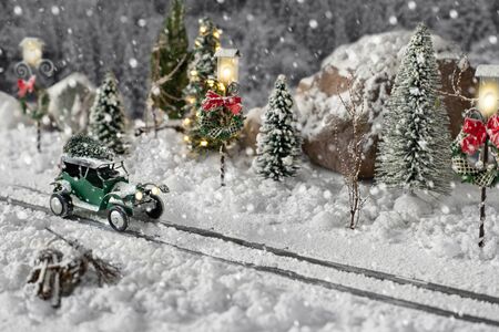 Miniature classic car carrying a christmas tree on snowy road on winter magic backgroundの写真素材