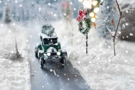 Miniature classic car carrying a christmas tree on snowy road on winter backgroundの写真素材