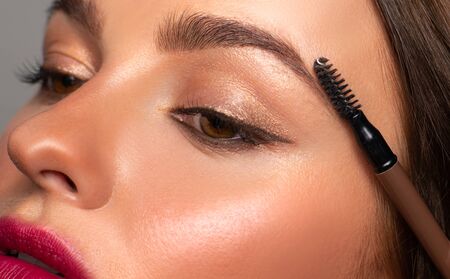Beautiful eyes of woman with amazing make up. Girl is applying makeup on eyebrowsの写真素材