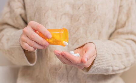 Woman takes pills vitamins. Woman is holding a jar of pills her handsの写真素材