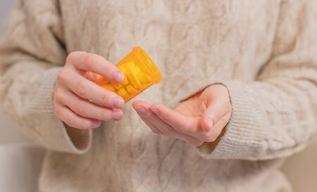 Woman takes pills vitamins. Woman is holding a jar of pills her handsの写真素材