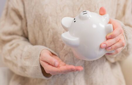 Woman is shaking piggy bank. Financial problem conceptの写真素材