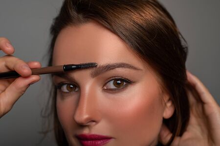 Beautiful eyes of woman with amazing make up. Girl is applying makeup on eyebrowsの写真素材