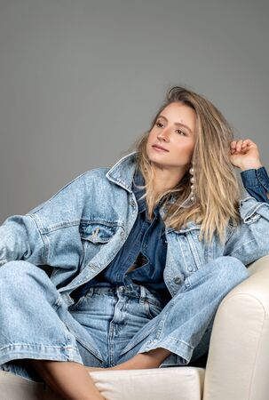 Fashionable clothes. Beautiful woman in jeans and a denim shirt in studioの写真素材