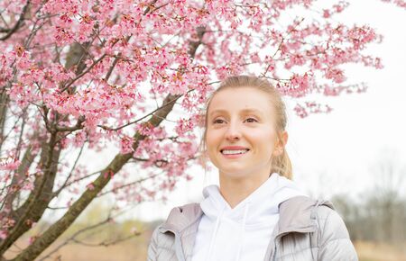 Beginning of Spring. Beautiful woman enjoying nature blooming tree. Spring allergy conceptの写真素材