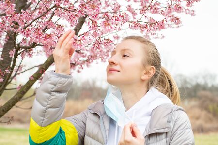 Beginning of Spring. Beautiful woman enjoying nature blooming tree. Spring allergy conceptの写真素材